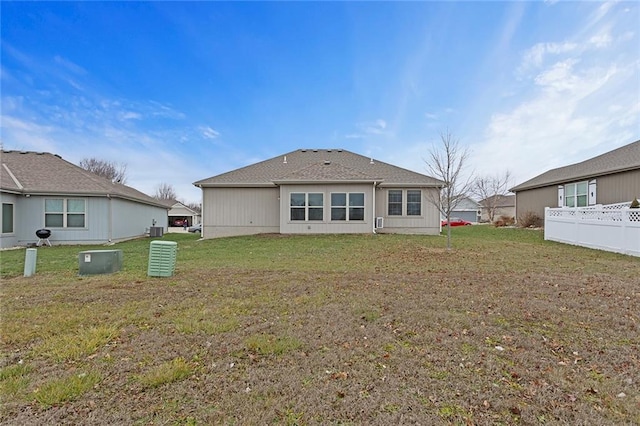 back of property with a lawn and fence