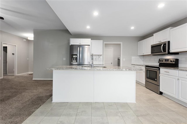 kitchen featuring appliances with stainless steel finishes, a sink, a center island with sink, and white cabinets