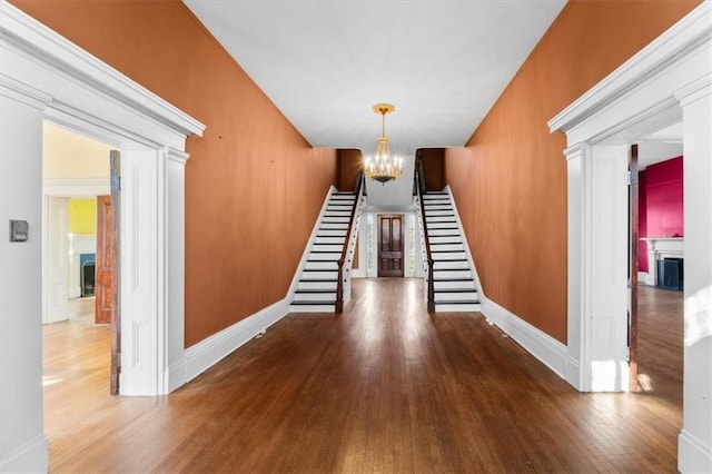 stairs with a fireplace, baseboards, an inviting chandelier, and wood finished floors