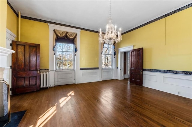 unfurnished dining area with a wealth of natural light, a notable chandelier, radiator, and wood finished floors