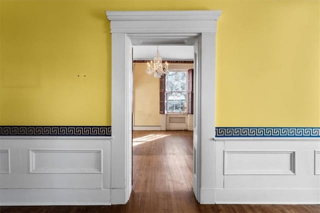 hallway featuring a notable chandelier, dark wood-style floors, and baseboard heating