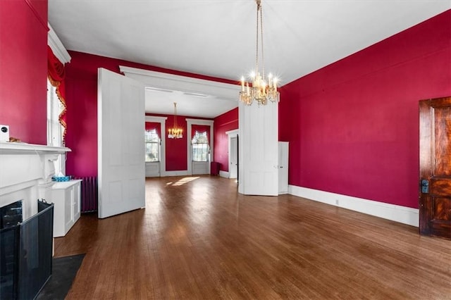 dining room featuring a notable chandelier, baseboards, a fireplace with flush hearth, and wood finished floors