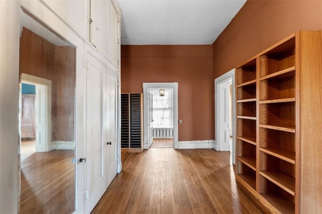 corridor featuring hardwood / wood-style floors and baseboards