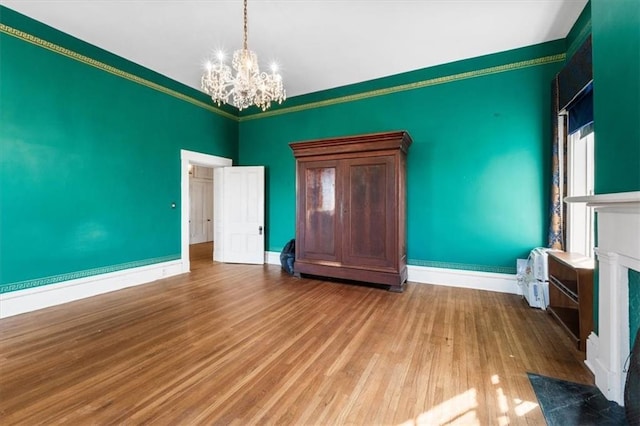 interior space featuring wood finished floors, baseboards, an inviting chandelier, and ornamental molding