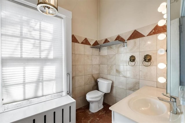 bathroom with toilet, tile walls, and vanity