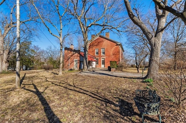 back of property featuring a chimney and a yard