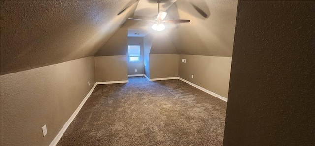 additional living space with dark colored carpet, ceiling fan, lofted ceiling, and a textured ceiling