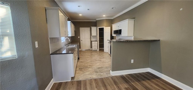 kitchen with dark hardwood / wood-style flooring, white cabinetry, sink, and ornamental molding