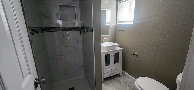 bathroom featuring a tile shower, vanity, and toilet