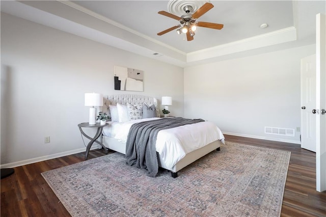 bedroom featuring ornamental molding, ceiling fan, a tray ceiling, and dark hardwood / wood-style floors