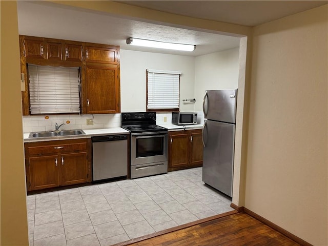 kitchen featuring backsplash, light wood-type flooring, sink, and appliances with stainless steel finishes