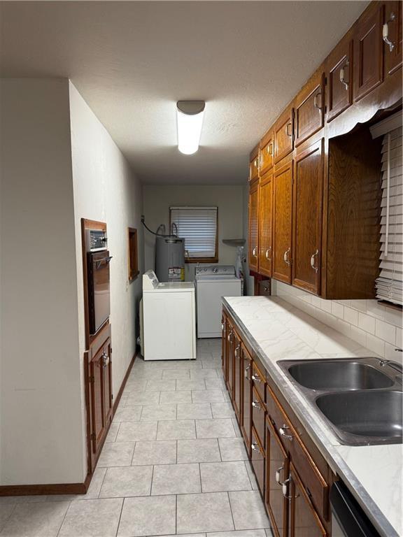 kitchen featuring sink, gas water heater, separate washer and dryer, stainless steel dishwasher, and oven