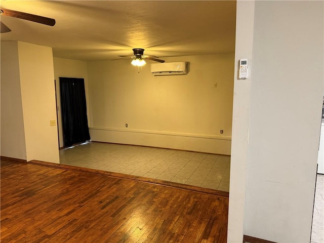 spare room with a wall mounted air conditioner, light wood-type flooring, and ceiling fan