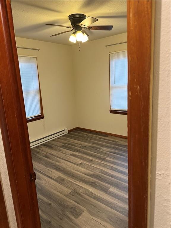 empty room with a baseboard radiator, dark hardwood / wood-style floors, and ceiling fan