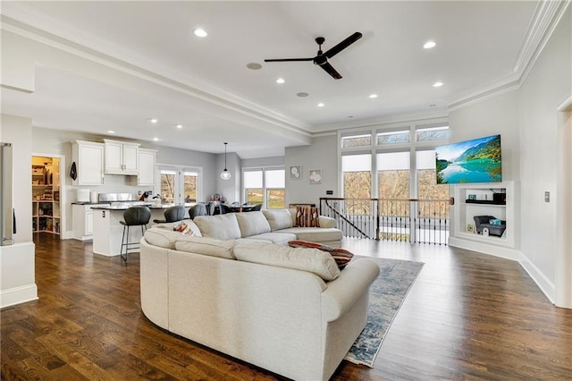 living room featuring dark hardwood / wood-style floors, ceiling fan, and ornamental molding