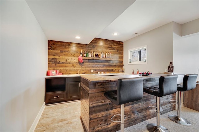 bar featuring wood walls and dark brown cabinetry