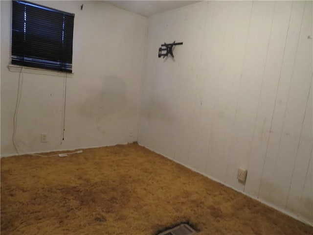 spare room with carpet flooring and wooden walls