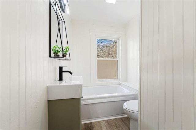 bathroom with hardwood / wood-style flooring, vanity, a bath, and toilet