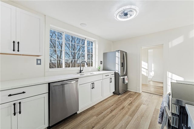 kitchen featuring sink, light hardwood / wood-style flooring, white cabinets, and appliances with stainless steel finishes