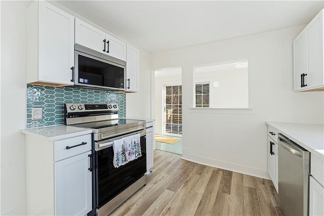 kitchen featuring backsplash, appliances with stainless steel finishes, light wood-type flooring, and white cabinets