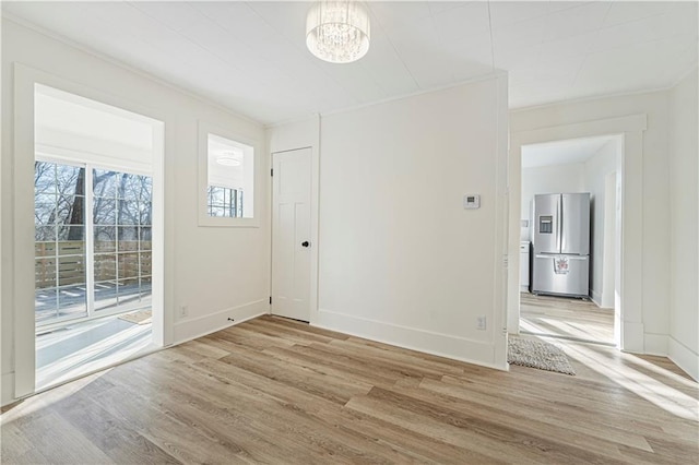 spare room with a notable chandelier and light wood-type flooring