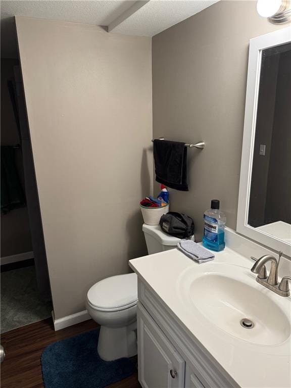 bathroom featuring vanity, hardwood / wood-style floors, toilet, and a textured ceiling