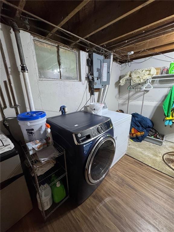 washroom with hardwood / wood-style flooring, washing machine and clothes dryer, and electric panel