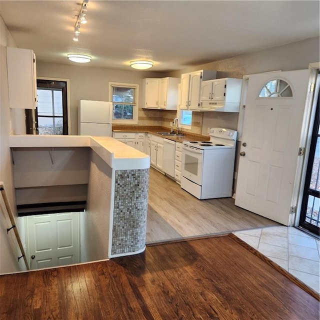 kitchen with white cabinets, light hardwood / wood-style floors, white appliances, and sink