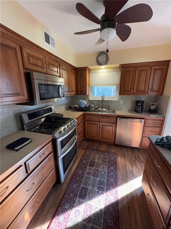 kitchen with sink, tasteful backsplash, appliances with stainless steel finishes, dark hardwood / wood-style floors, and ceiling fan