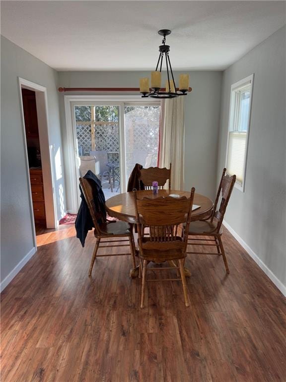 dining room with dark wood-type flooring, a notable chandelier, and a wealth of natural light