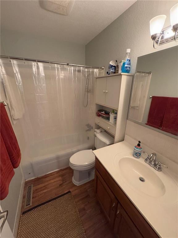 full bathroom featuring wood-type flooring, shower / bath combination with curtain, vanity, toilet, and a textured ceiling