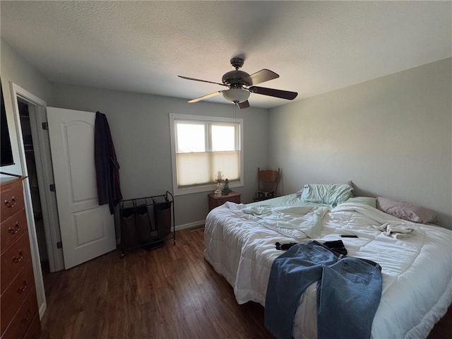 bedroom with dark wood-type flooring, ceiling fan, and a textured ceiling