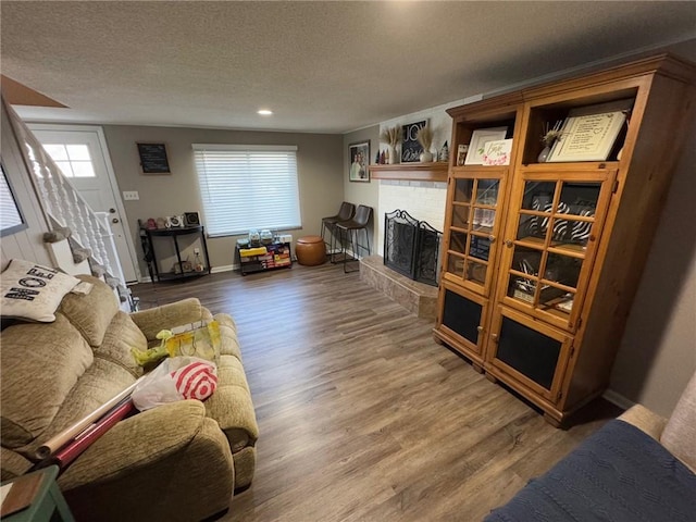 living room featuring hardwood / wood-style flooring, a brick fireplace, and a textured ceiling