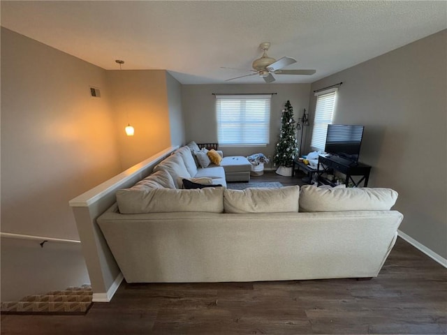 living room featuring ceiling fan, dark hardwood / wood-style floors, and a textured ceiling