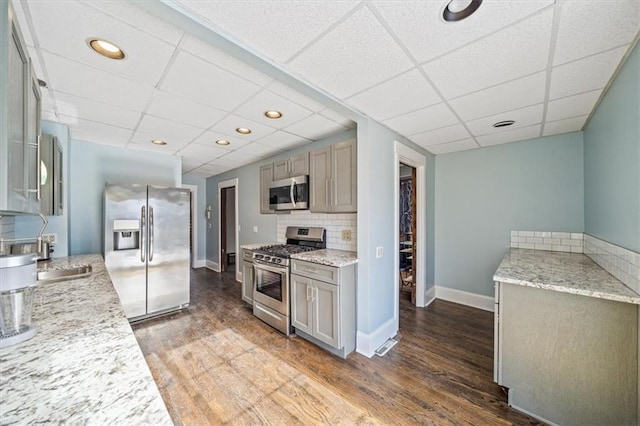 kitchen with dark hardwood / wood-style flooring, backsplash, a paneled ceiling, and stainless steel appliances