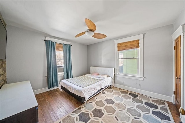 bedroom featuring ceiling fan, hardwood / wood-style flooring, and multiple windows