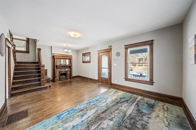 foyer entrance featuring a notable chandelier, hardwood / wood-style flooring, and a stone fireplace