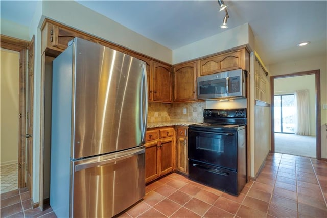 kitchen with decorative backsplash, light tile patterned floors, stainless steel appliances, and light stone counters