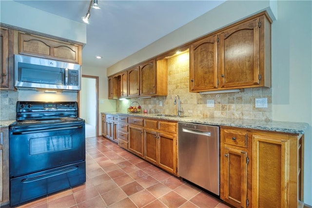 kitchen with sink, stainless steel appliances, tasteful backsplash, tile patterned floors, and track lighting