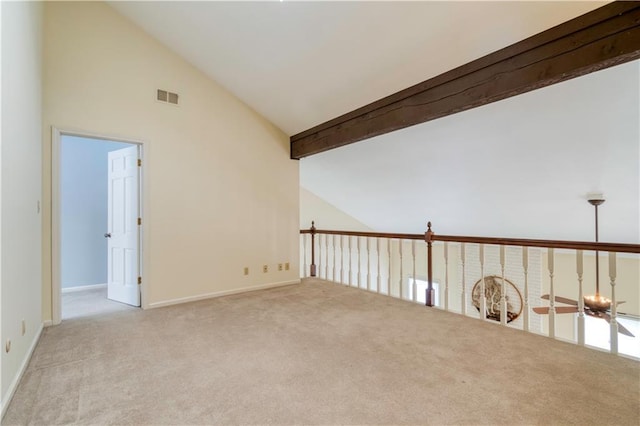 spare room with beam ceiling, light colored carpet, and high vaulted ceiling