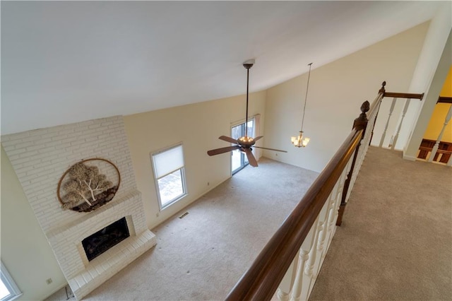 carpeted living room featuring ceiling fan, lofted ceiling, and a brick fireplace