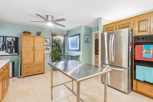 kitchen with stainless steel fridge, black double oven, and ceiling fan