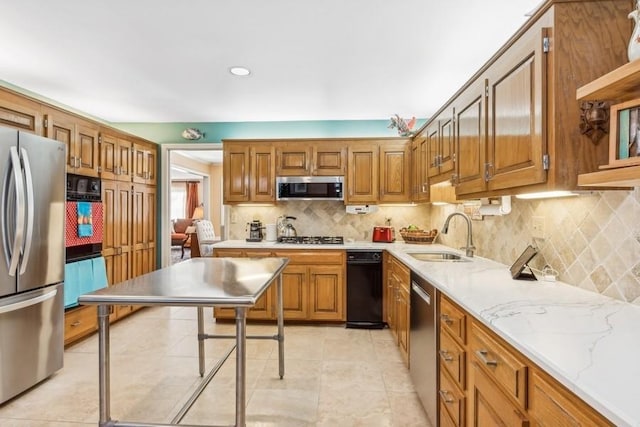 kitchen with decorative backsplash, light stone countertops, sink, and appliances with stainless steel finishes