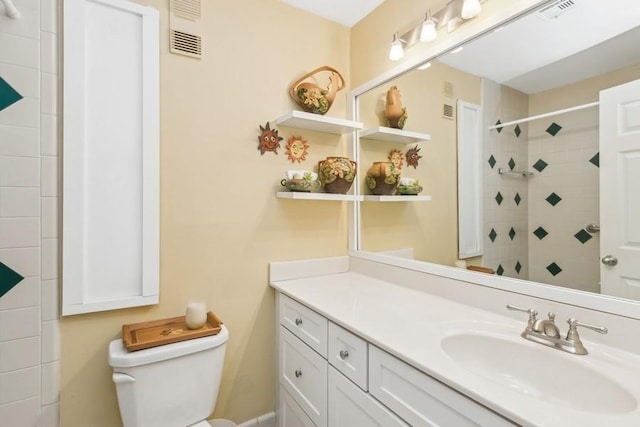 bathroom featuring a tile shower, vanity, and toilet