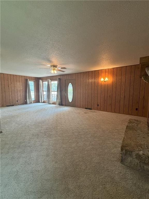 unfurnished living room featuring a textured ceiling, carpet floors, and ceiling fan