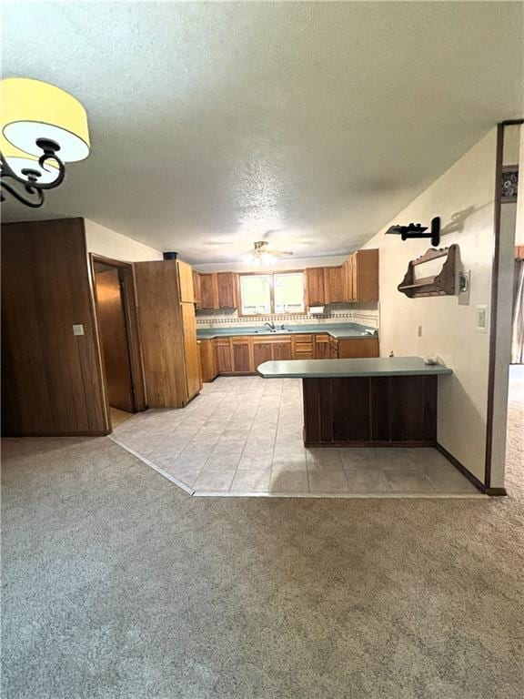 kitchen featuring kitchen peninsula, light carpet, a textured ceiling, and sink