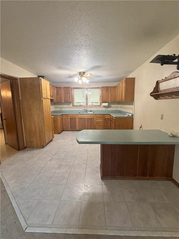 kitchen with kitchen peninsula, sink, and a textured ceiling