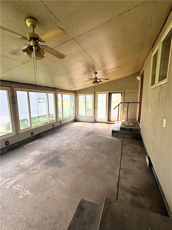 unfurnished sunroom with ceiling fan and vaulted ceiling