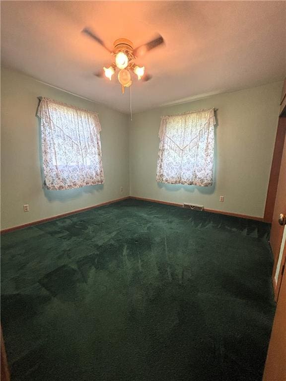 carpeted empty room with a wealth of natural light and ceiling fan