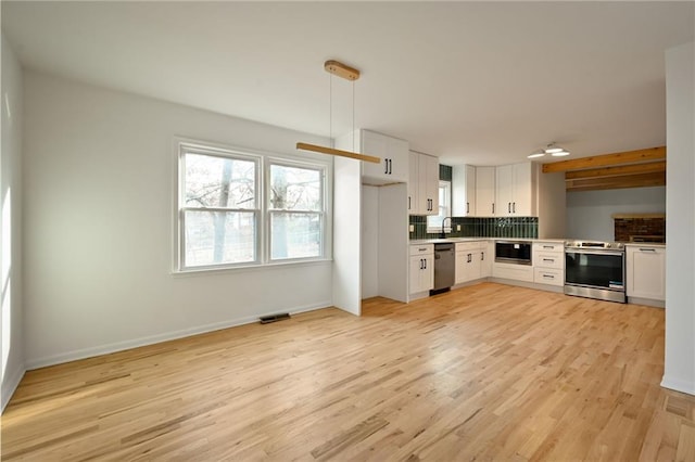 kitchen featuring white cabinets, sink, light wood-type flooring, decorative light fixtures, and stainless steel appliances